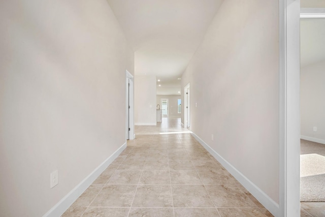 hallway featuring light tile patterned floors and baseboards