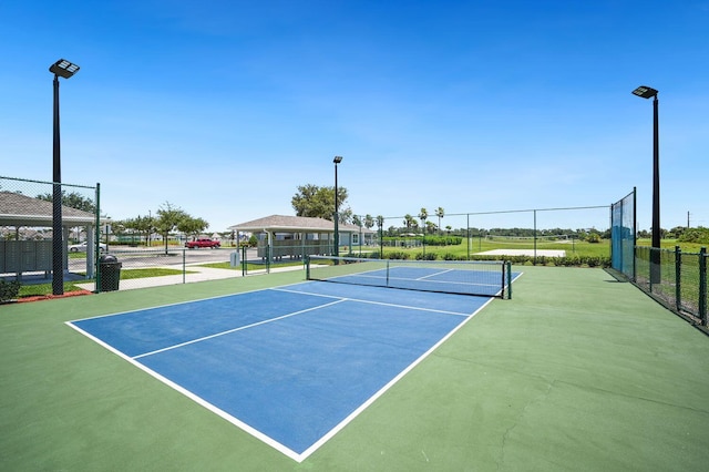 view of tennis court with community basketball court and fence