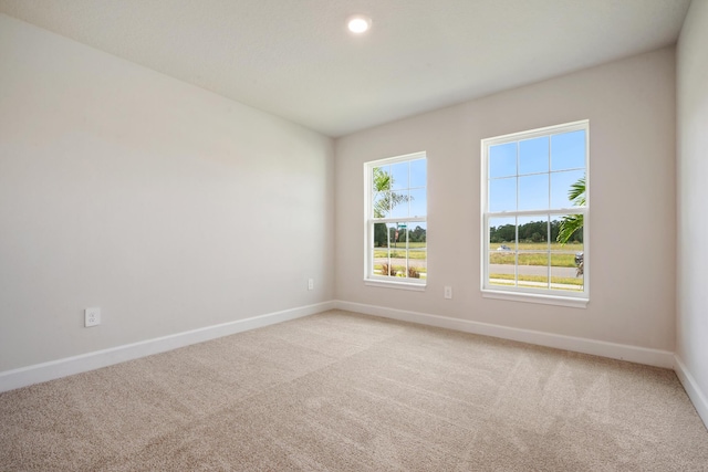 empty room featuring baseboards and light carpet