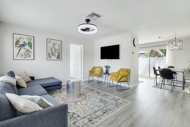 living area with an inviting chandelier, wood finished floors, visible vents, and baseboards