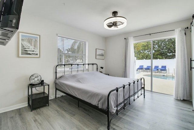 bedroom featuring multiple windows, wood finished floors, and access to outside