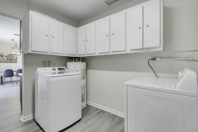 washroom featuring washer and dryer, light wood-style flooring, cabinet space, and water heater