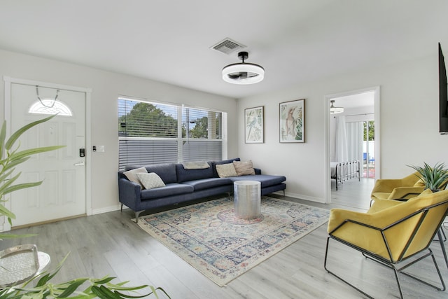 living area with wood finished floors, a healthy amount of sunlight, visible vents, and baseboards