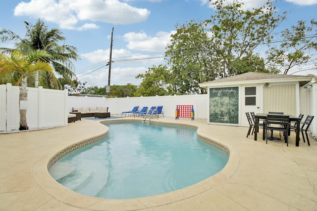 view of pool featuring a fenced in pool, outdoor lounge area, a fenced backyard, a patio area, and an outbuilding