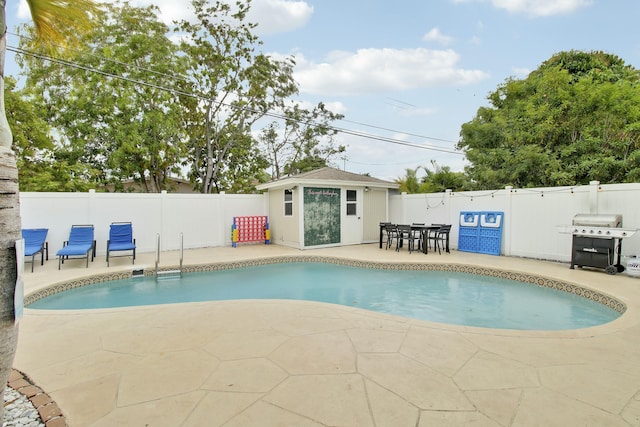 view of swimming pool with an outbuilding, area for grilling, a fenced backyard, and a patio