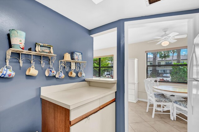 kitchen with light tile patterned floors, visible vents, freestanding refrigerator, and a ceiling fan