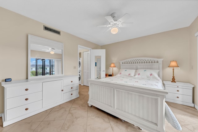 bedroom with visible vents, stacked washer / drying machine, and a ceiling fan