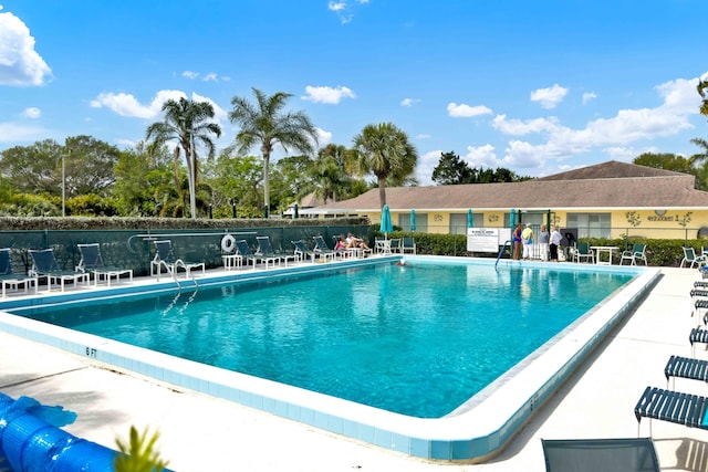 community pool with a patio area and fence