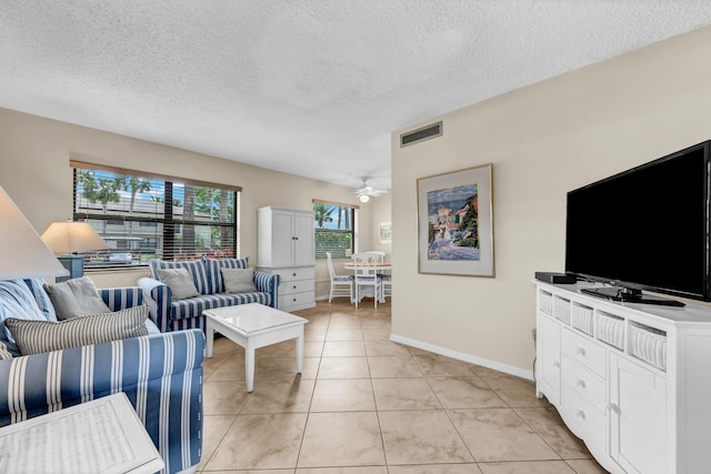 living area with visible vents, baseboards, light tile patterned floors, a textured ceiling, and a ceiling fan