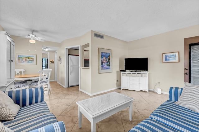 living room with visible vents, baseboards, light tile patterned floors, a textured ceiling, and a ceiling fan