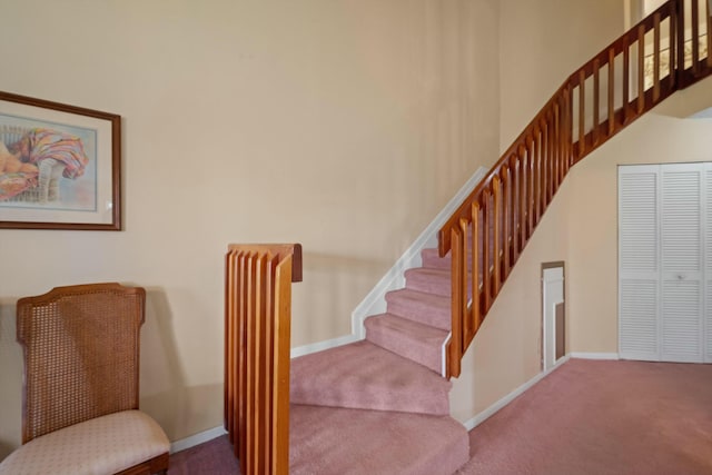 stairway with a high ceiling, baseboards, and carpet floors