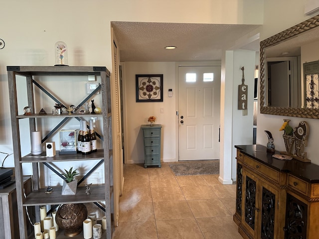 entryway featuring baseboards, a textured ceiling, and light tile patterned flooring