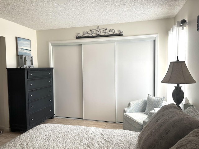 bedroom featuring light tile patterned flooring, a textured ceiling, and a closet