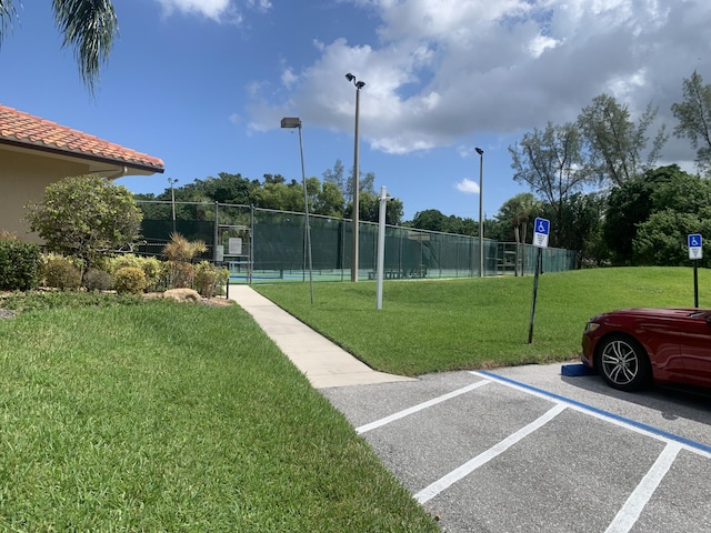 surrounding community featuring a lawn, fence, and uncovered parking
