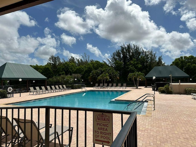 community pool with a patio area and fence