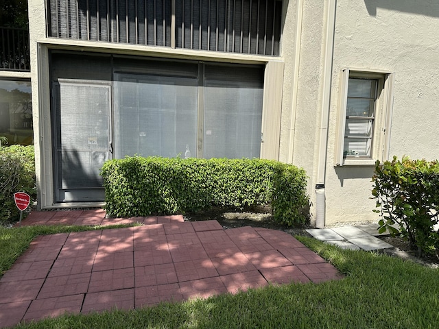 view of exterior entry featuring stucco siding and a patio area