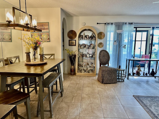 tiled dining area featuring arched walkways and a textured ceiling