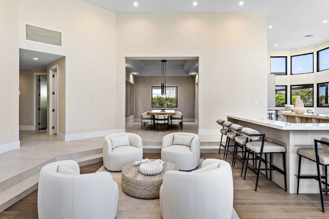 living area with visible vents, recessed lighting, a high ceiling, and baseboards