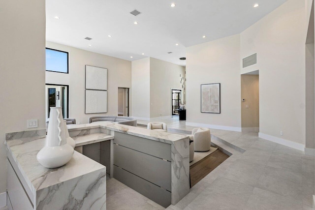 kitchen with light stone counters, visible vents, modern cabinets, and a towering ceiling