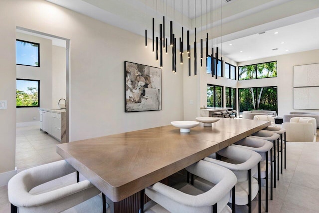 dining room featuring a wealth of natural light, light tile patterned floors, and a towering ceiling