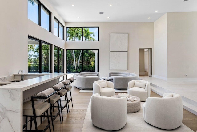 living room featuring a towering ceiling, recessed lighting, visible vents, and light wood finished floors