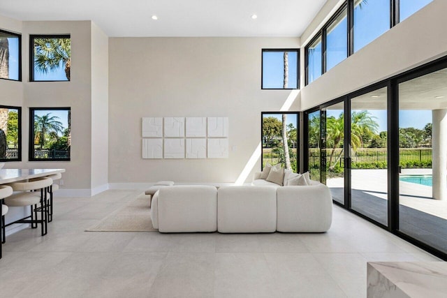 living room with light tile patterned floors, recessed lighting, a high ceiling, and baseboards