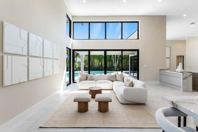 living area featuring recessed lighting, baseboards, and a towering ceiling