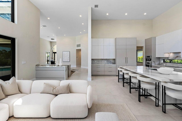 living area with a high ceiling, recessed lighting, visible vents, and a wealth of natural light