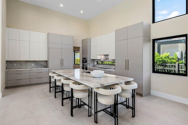 kitchen featuring a kitchen bar, a high ceiling, and gray cabinetry