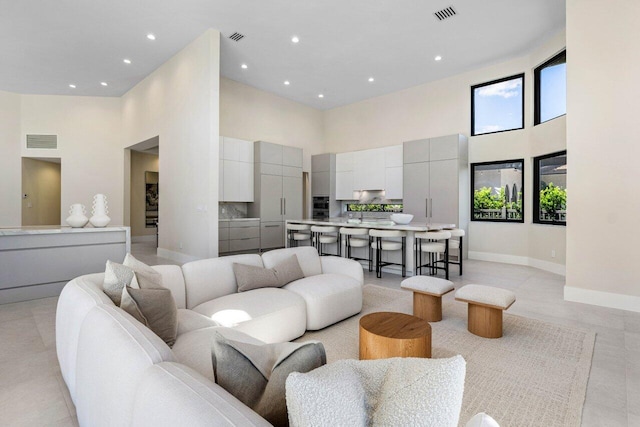 living area with visible vents, recessed lighting, and a towering ceiling