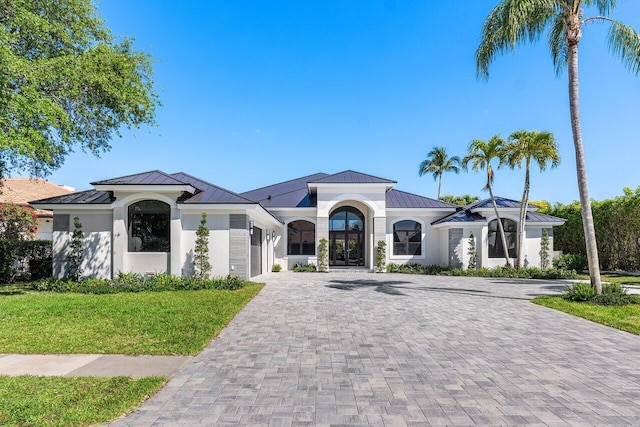 mediterranean / spanish-style house featuring a standing seam roof, decorative driveway, and metal roof