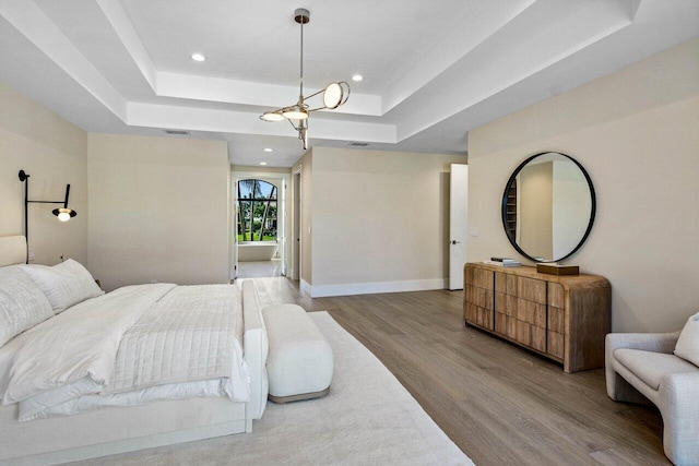 bedroom featuring visible vents, baseboards, a tray ceiling, recessed lighting, and wood finished floors