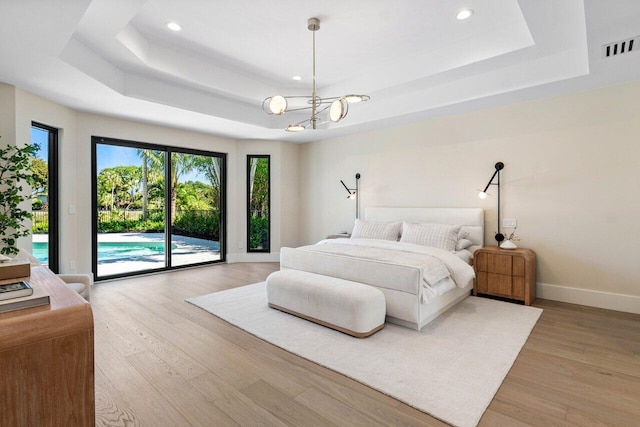 bedroom featuring visible vents, light wood-style flooring, access to outside, a tray ceiling, and baseboards