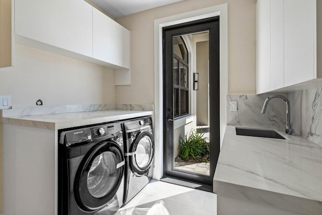 washroom with cabinet space, independent washer and dryer, and a sink