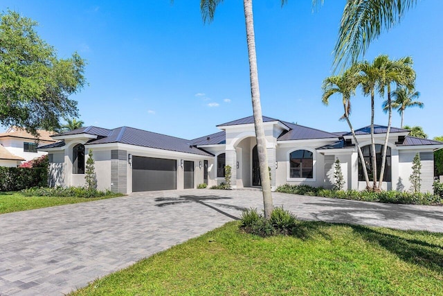 view of front facade with metal roof, decorative driveway, a garage, and a standing seam roof