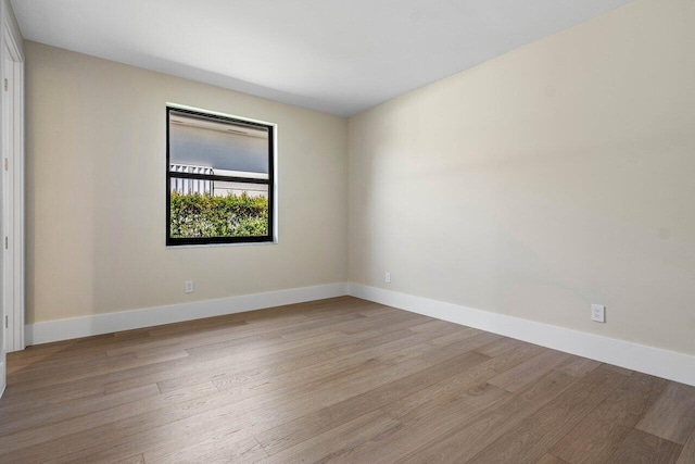 empty room featuring baseboards and light wood-type flooring