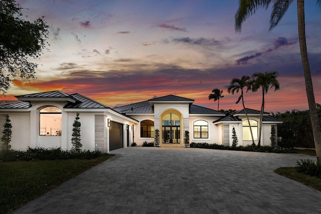 view of front of house featuring metal roof, decorative driveway, an attached garage, and a standing seam roof