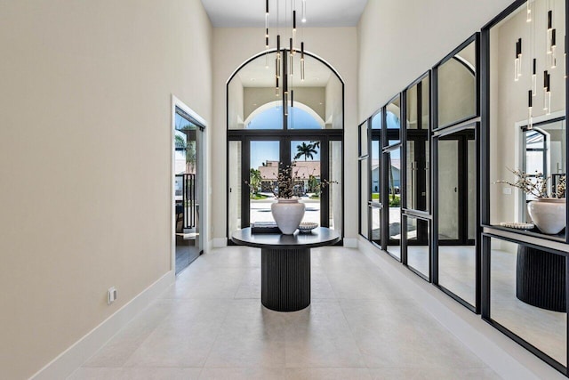 foyer with french doors, baseboards, and a towering ceiling