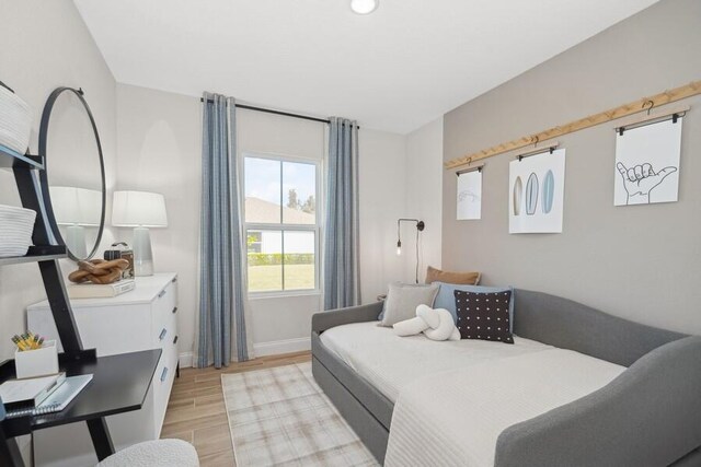 bedroom with light wood finished floors and baseboards