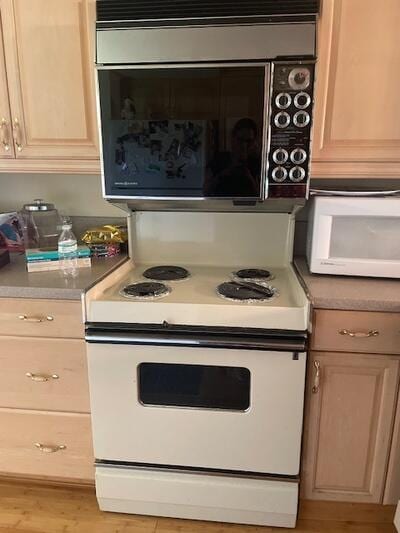 kitchen featuring white appliances, light countertops, light brown cabinetry, and light wood finished floors