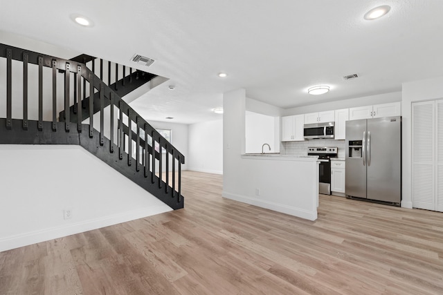 kitchen featuring visible vents, backsplash, white cabinetry, appliances with stainless steel finishes, and light wood finished floors