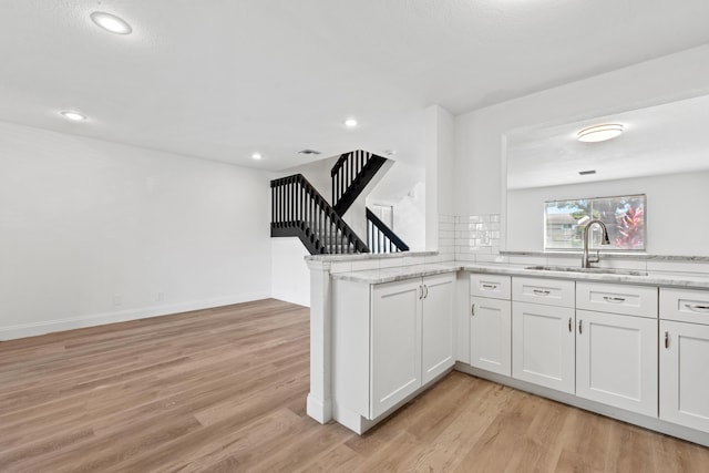 kitchen featuring light stone counters, light wood-style floors, and a sink