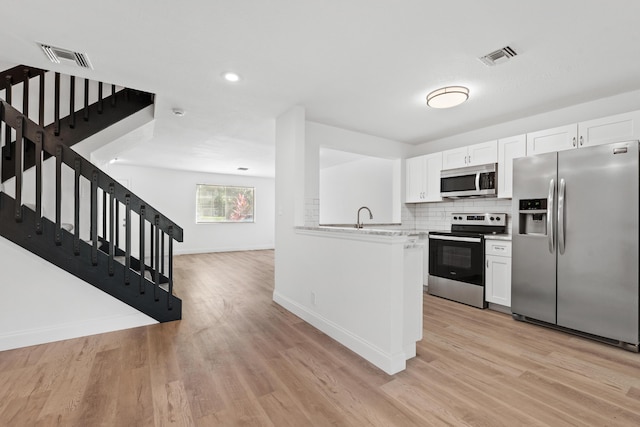 kitchen featuring stainless steel appliances, tasteful backsplash, light countertops, and white cabinetry