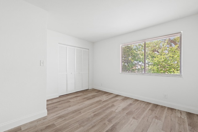 unfurnished bedroom with a closet, baseboards, and light wood finished floors