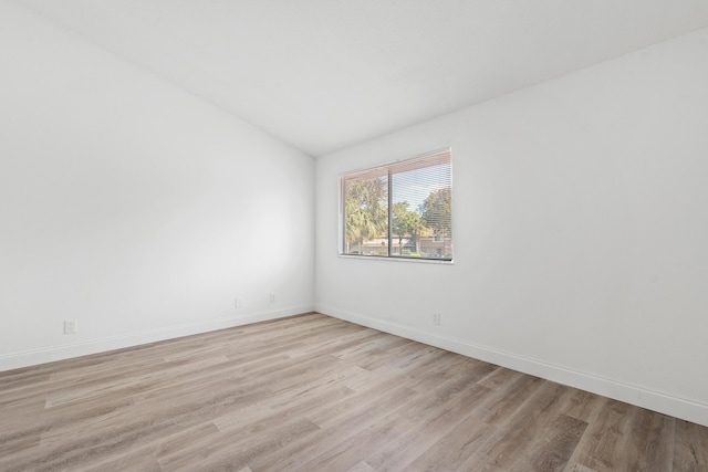 unfurnished room with baseboards, lofted ceiling, and light wood-style flooring