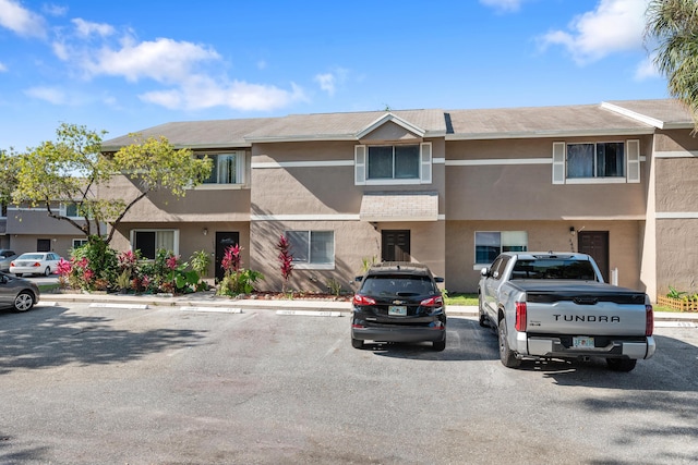 view of property with stucco siding and uncovered parking