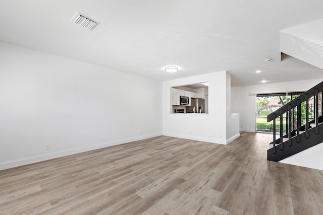 unfurnished living room with light wood-type flooring, visible vents, recessed lighting, stairway, and baseboards