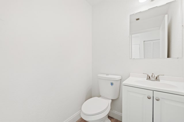 half bath with baseboards, toilet, wood finished floors, and vanity