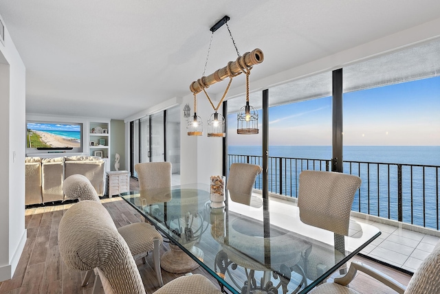 dining space featuring built in shelves, wood finished floors, and a water view