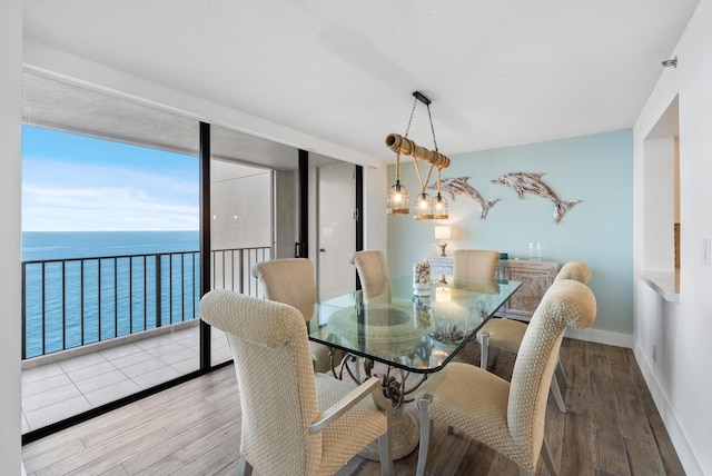 dining space with expansive windows, a water view, baseboards, and wood finished floors